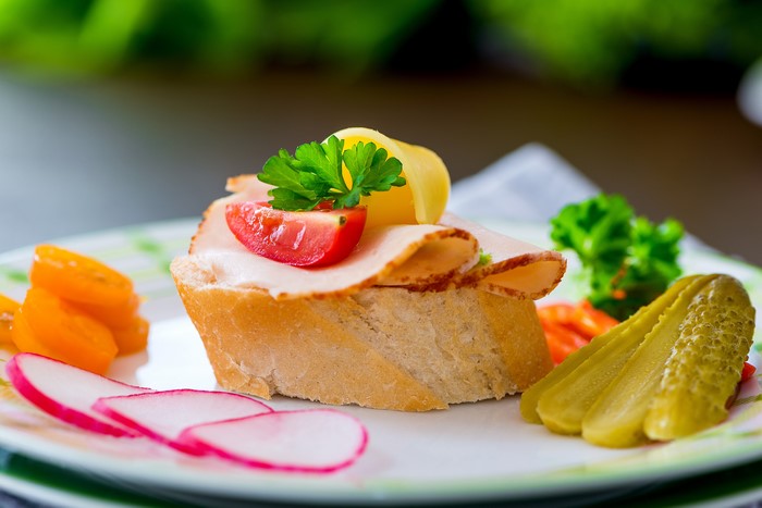 Open-faced sandwich with ham, tomato, and pickles