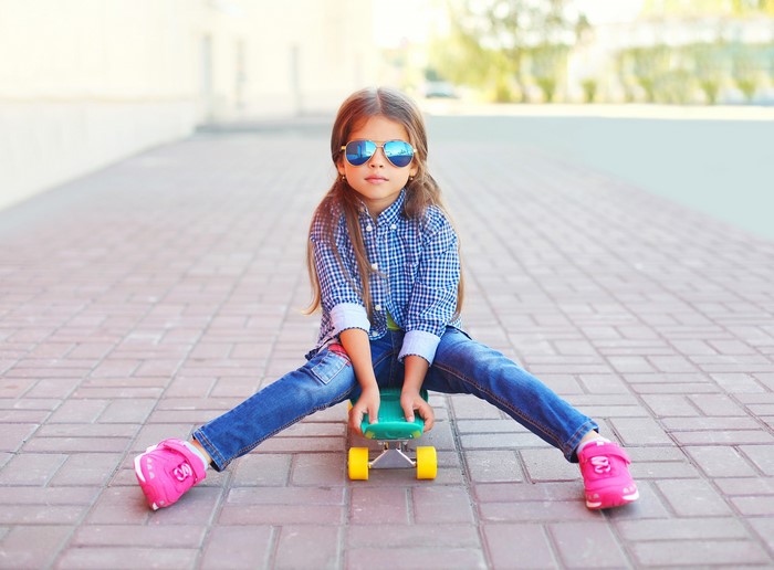 Girl in sunglasses sitting on a skateboard
