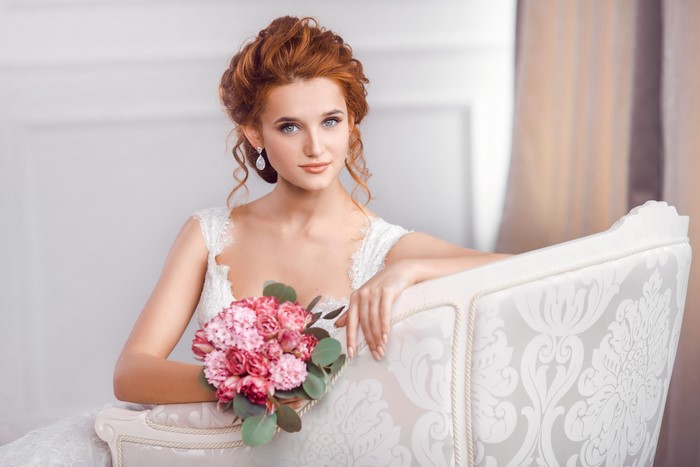 Redhead bride with bouquet sitting on a couch