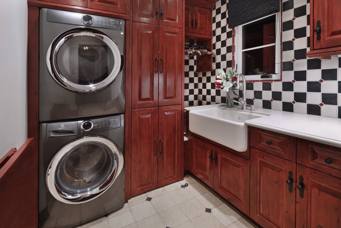 Laundry room with stacked washer and dryer, sink, and cabinets