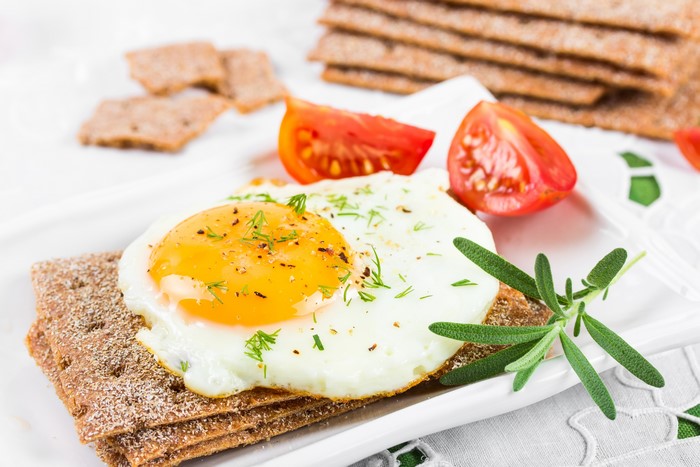 Fried egg on crispbread with tomatoes and rosemary