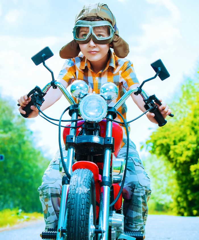 Boy wearing aviator helmet and goggles on a motorcycle