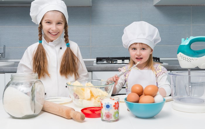 Two young girls in chef hats baking