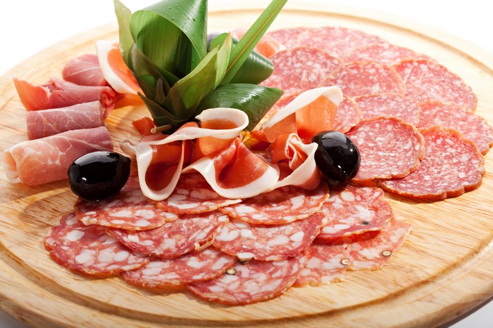 Meat platter with salami, ham, and olives on a cutting board