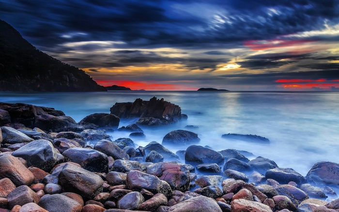 Rocky beach at sunset with dramatic clouds