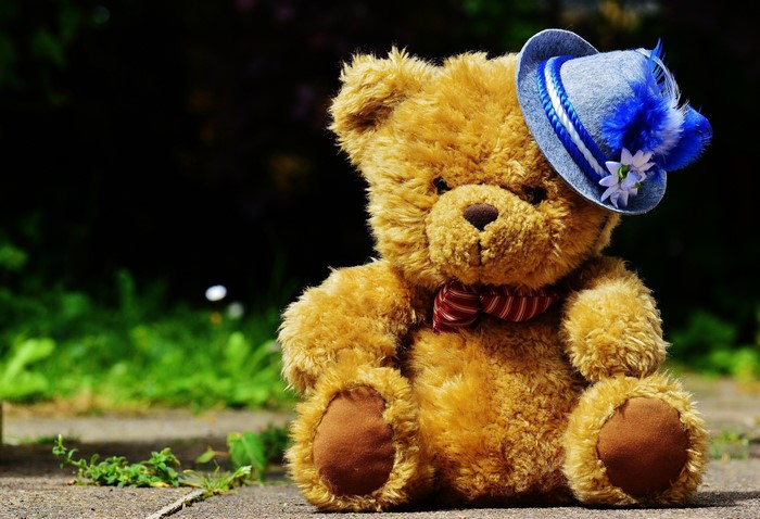 Teddy bear wearing a blue hat and red bowtie