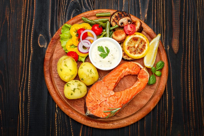 Salmon steak with potatoes and grilled vegetables on a cutting board