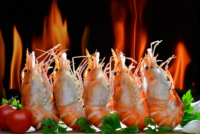 Shrimp grilling with flames and tomatoes