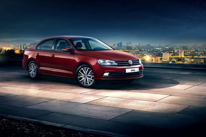 Red Volkswagen Jetta parked on a rooftop at night