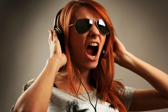 Redhead girl with headphones and sunglasses screaming