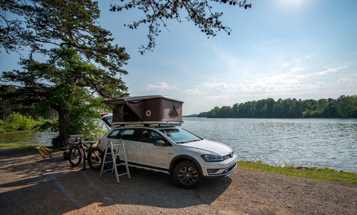 Volkswagen Golf Alltrack with rooftop tent by lake