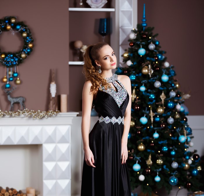 Woman in black dress by Christmas tree