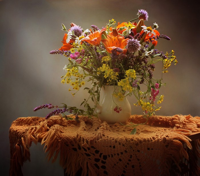 Bouquet of lilies and wildflowers in a vase on a table