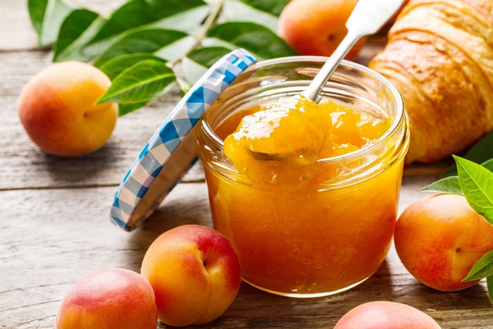 Apricot jam in a jar with fresh apricots and croissant