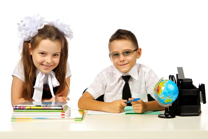 Two schoolchildren at a desk with books and a globe