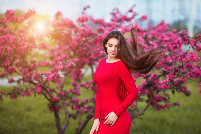 Woman in red dress near pink flowering tree