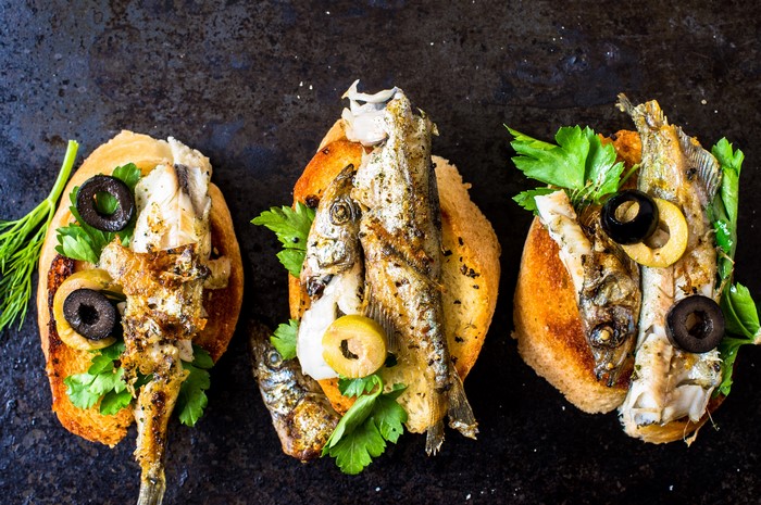 Toasted bread with grilled fish and olives