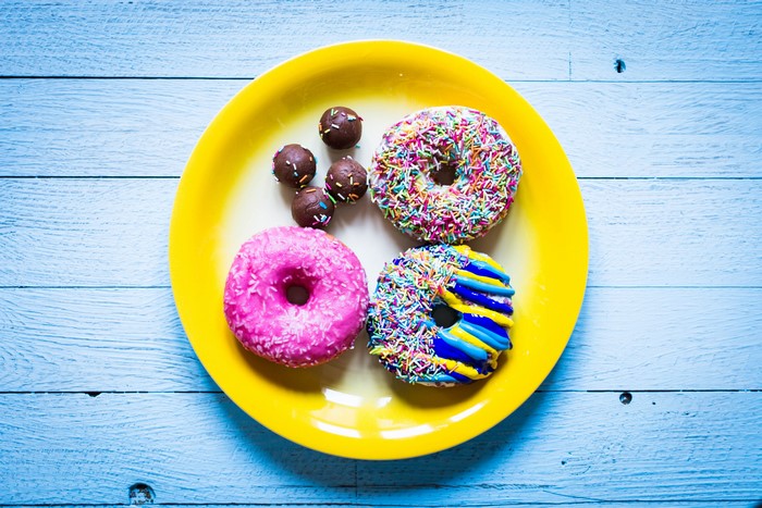 Donuts and chocolate balls on a yellow plate