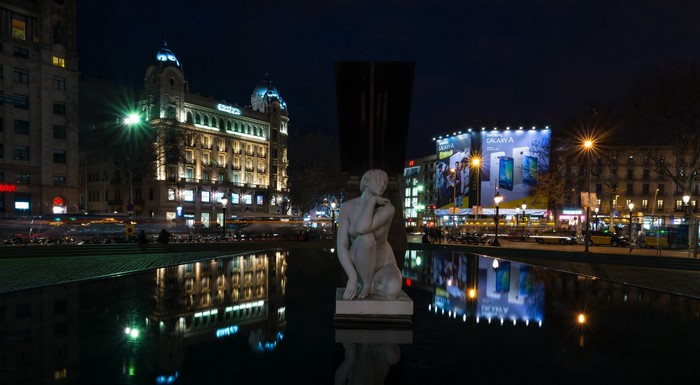 Barcelona night scene with sculpture and reflections