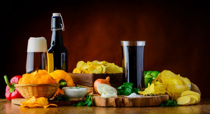Beer, Chips, and Vegetables on a Wooden Table