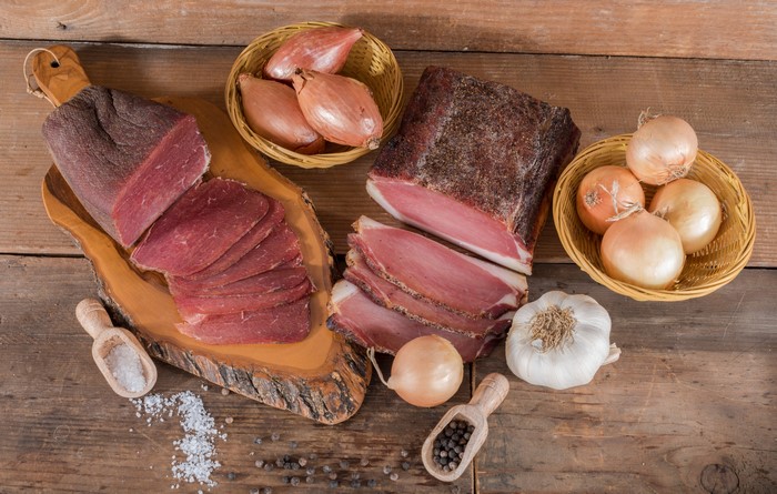 Meat products, ham, onion, garlic, and salt on wood