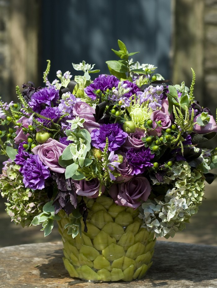 Purple and green floral arrangement in a textured vase