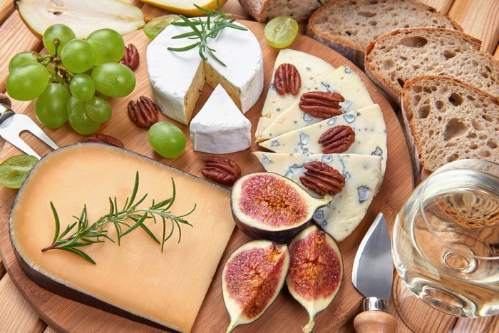 Cheese board with grapes, figs, nuts, bread, and wine