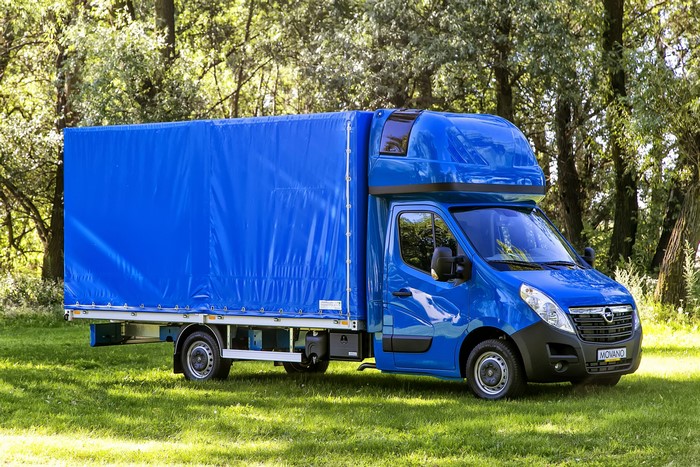 Blue Opel Movano truck with a blue tarp in a forest
