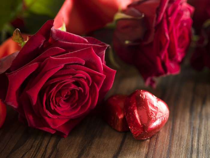 Red Roses and Heart Chocolates on Wooden Surface
