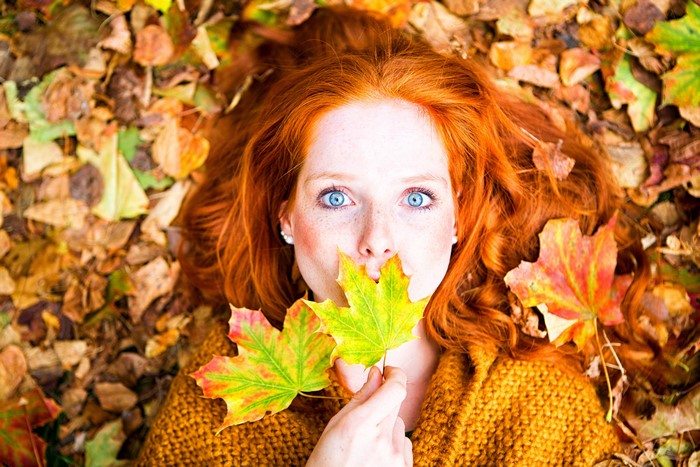 Redhead girl lying in autumn foliage