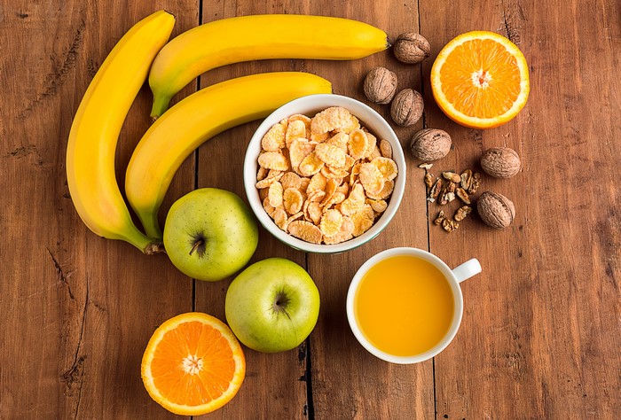 Breakfast with Bananas, Apples, Nuts, Orange Juice, and Cereal