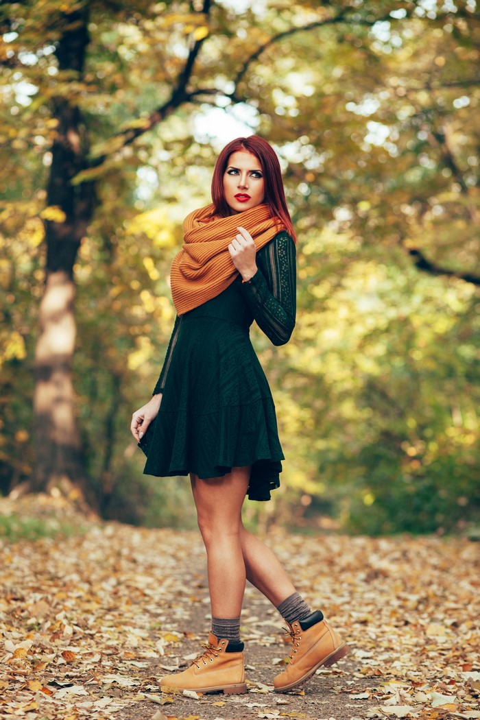 Woman in green dress and orange scarf in autumn forest
