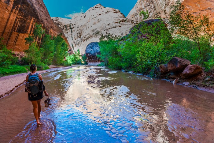 Woman hiking through a desert canyon stream