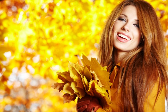 Woman holding autumn leaves with foliage background