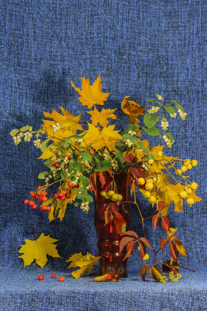 Autumn bouquet in a vase with maple leaves and berries