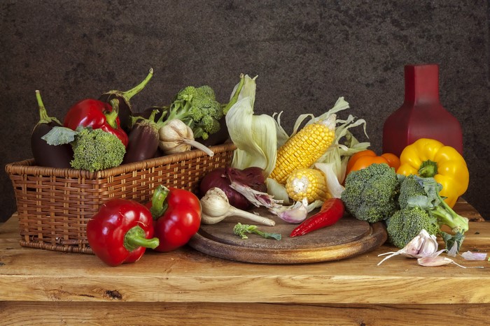 Still life of fresh vegetables in a basket and on a cutting board