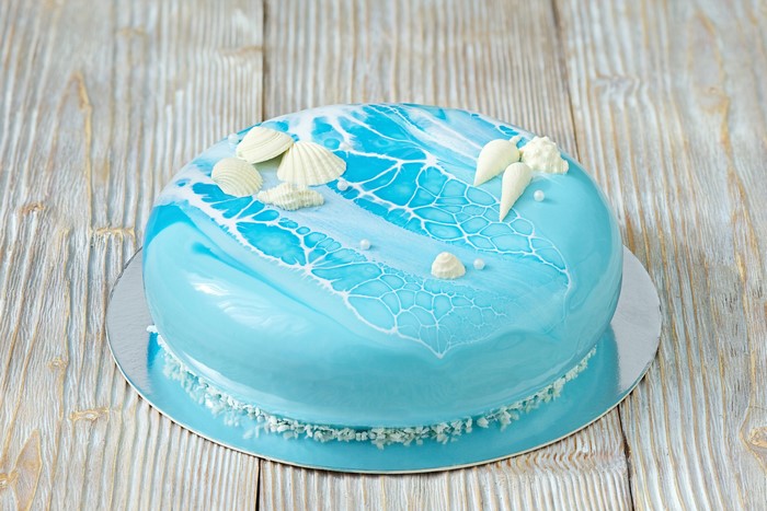 Light blue mirror glaze cake with seashell decorations