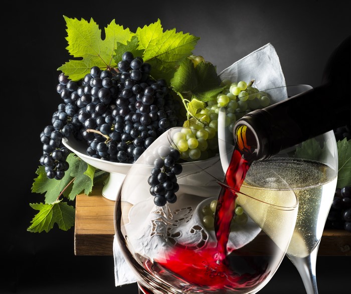 Red and white wine poured with grapes and stemware
