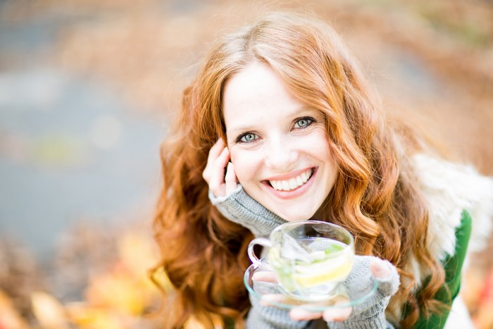 Redhead woman holding a cup of tea outdoors