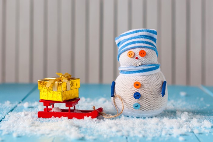 Snowman with gift on sled in snow