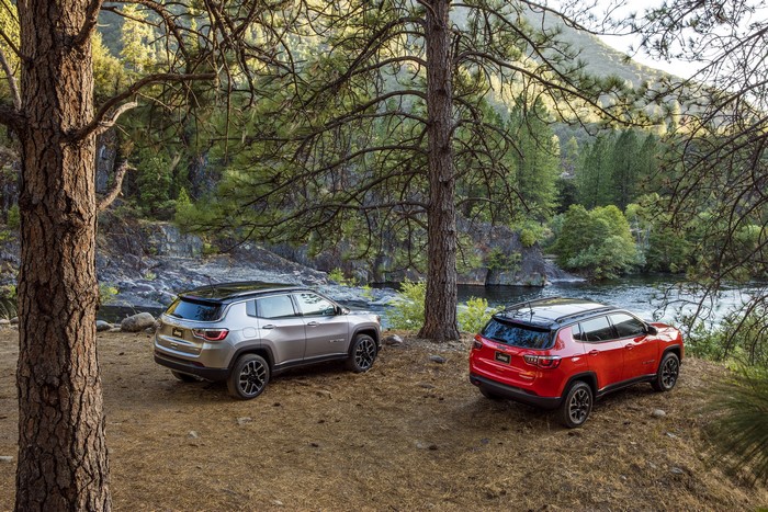 Two Jeep Compass SUVs parked by a river