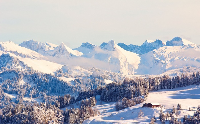 Snowy mountain range with a small cabin