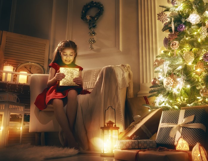 Girl Opening a Glowing Gift by Christmas Tree