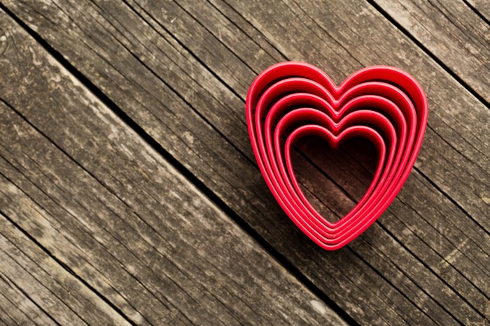 Stack of red heart cookie cutters on wood planks