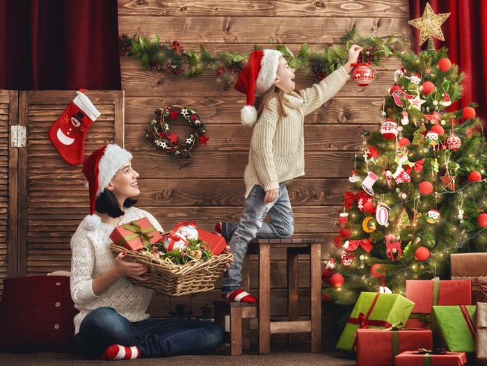 Mother and daughter decorating Christmas tree with gifts