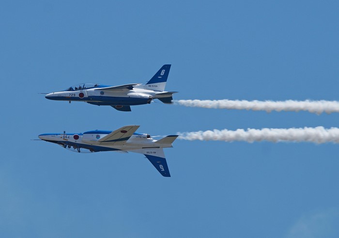 Two Kawasaki T-4 jets flying with smoke trails