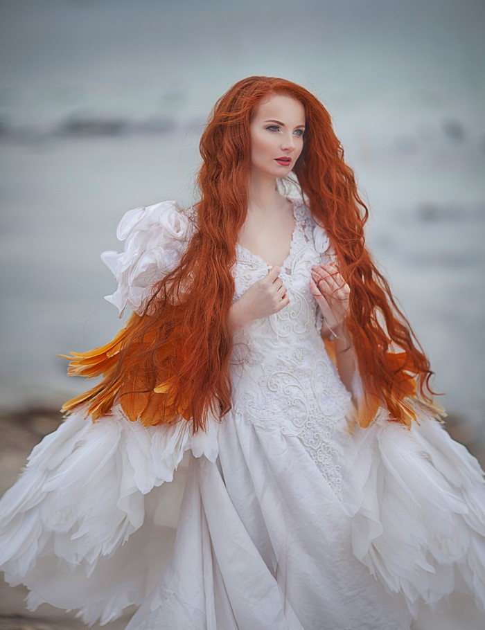 Redhead woman in a white dress with feather accents