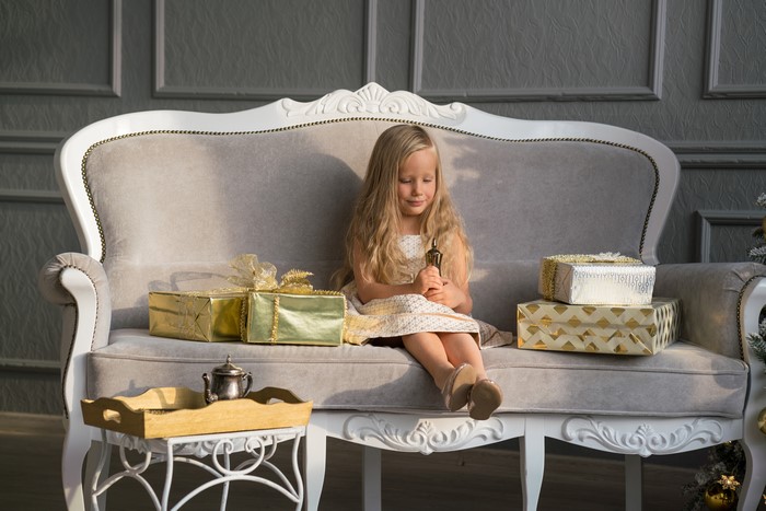 Little girl with Christmas gifts on a sofa