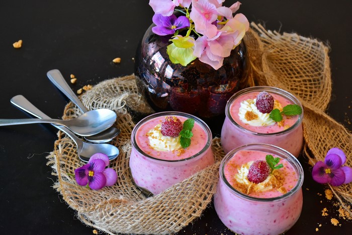 Raspberry desserts in glasses with spoons and flowers