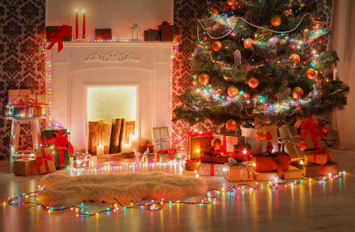 Christmas tree with fairy lights and gifts by fireplace